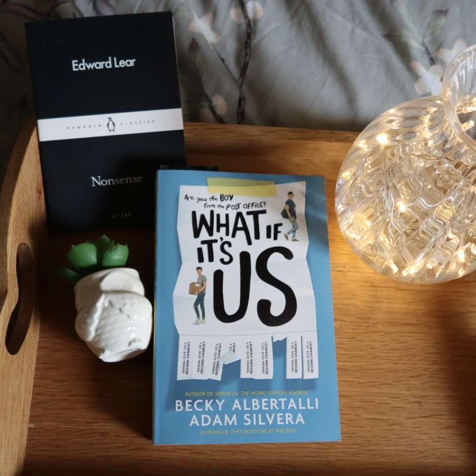 A photo of Nonsense by Edward Lear and What If It's Us by Becky Albertalli and Adam Silvera on a tray with an owl shaped plant pot and a vase full of lights.